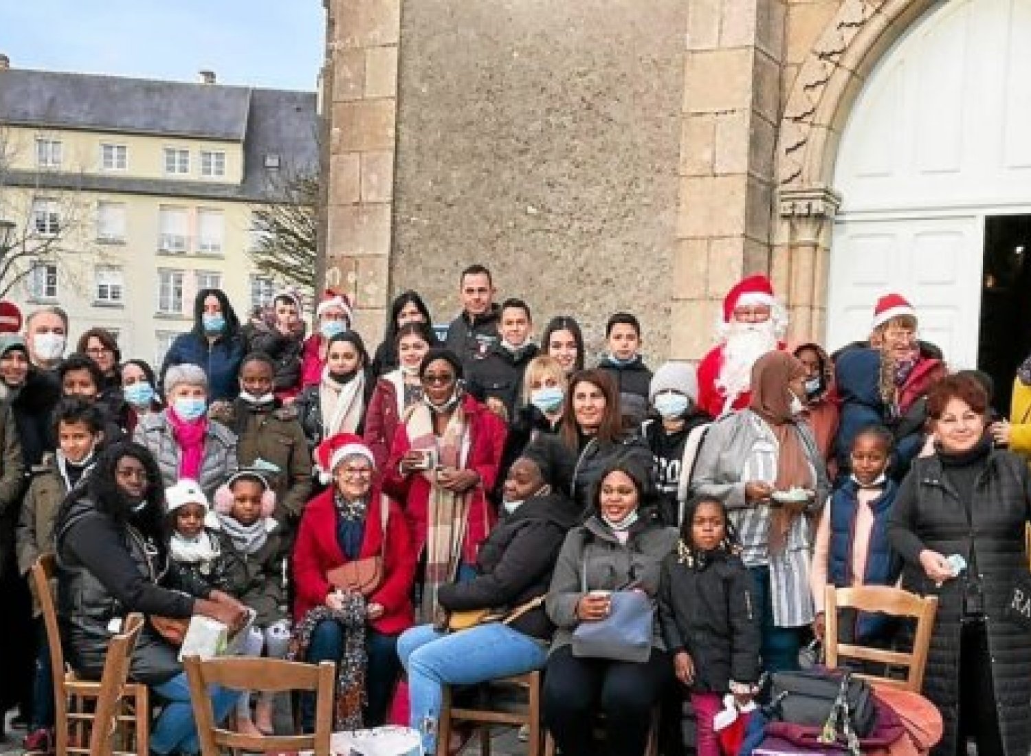Quelques-uns des migrants ayant participé au goûter de Noël devant la chapelle de Lourdes. (Photo source Annie Cueff du Secours catholique)